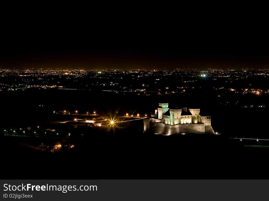 Torrechiara Castle by night, with the city of Parma in the background