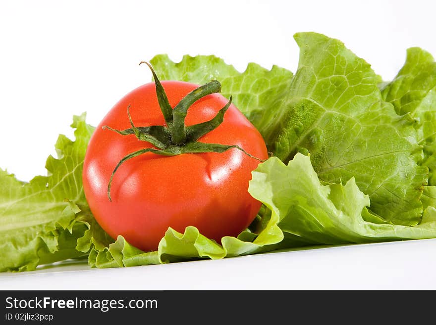 Red tomato in green leaves of salad. Red tomato in green leaves of salad