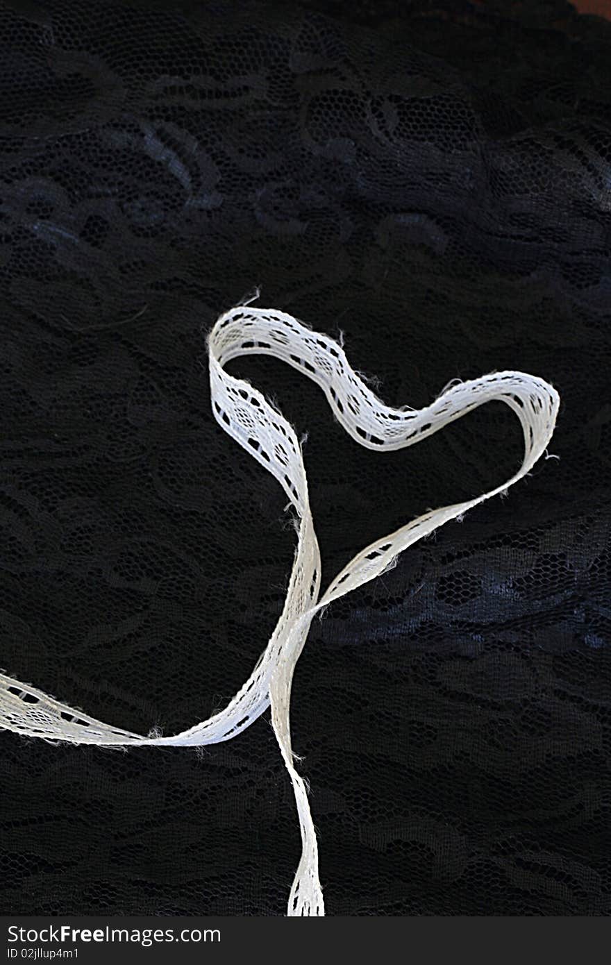 White lace shaped as a heart on black lace. White lace shaped as a heart on black lace.