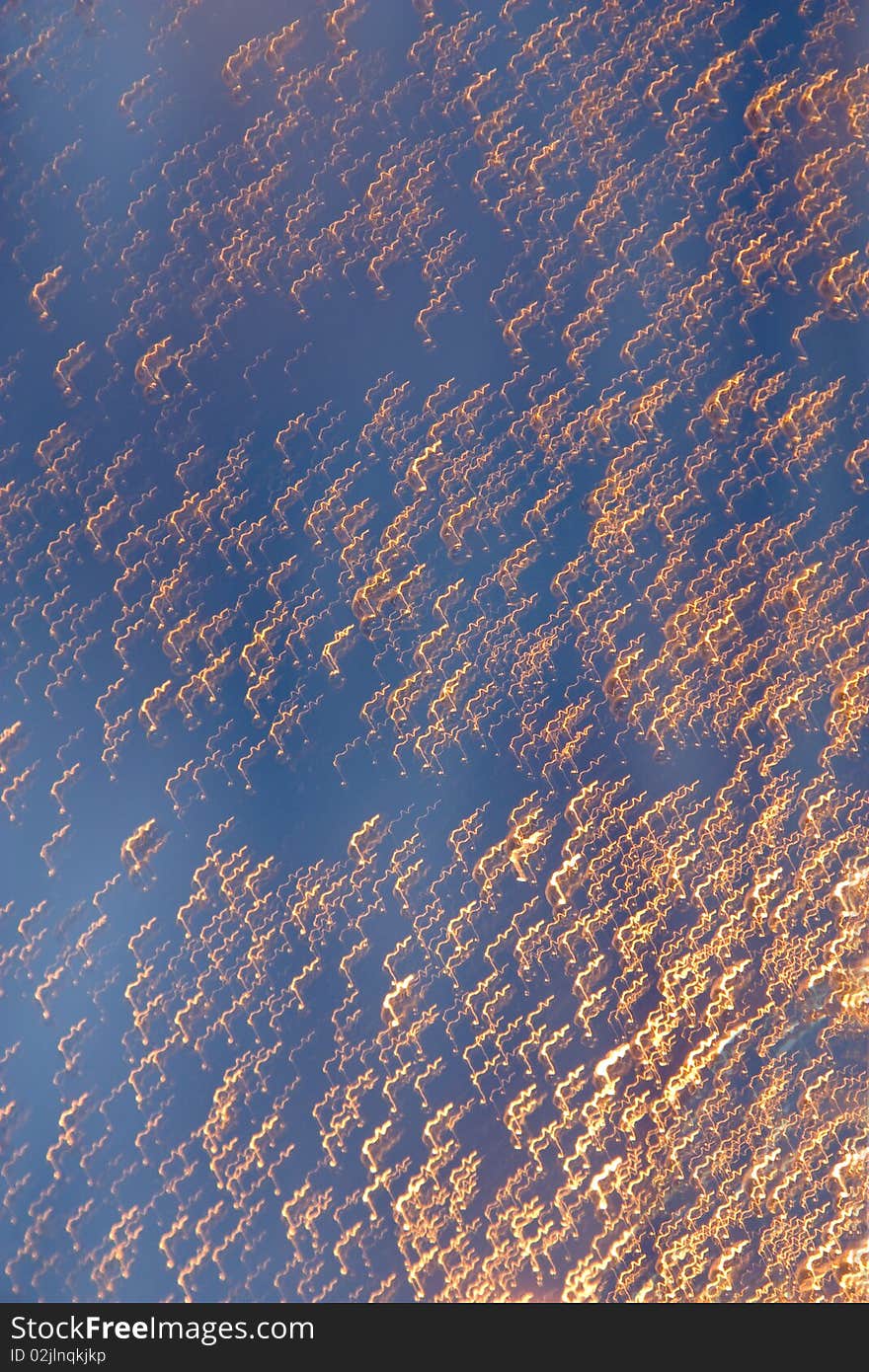 Running drops of a rain at light of a candle against the blue sky