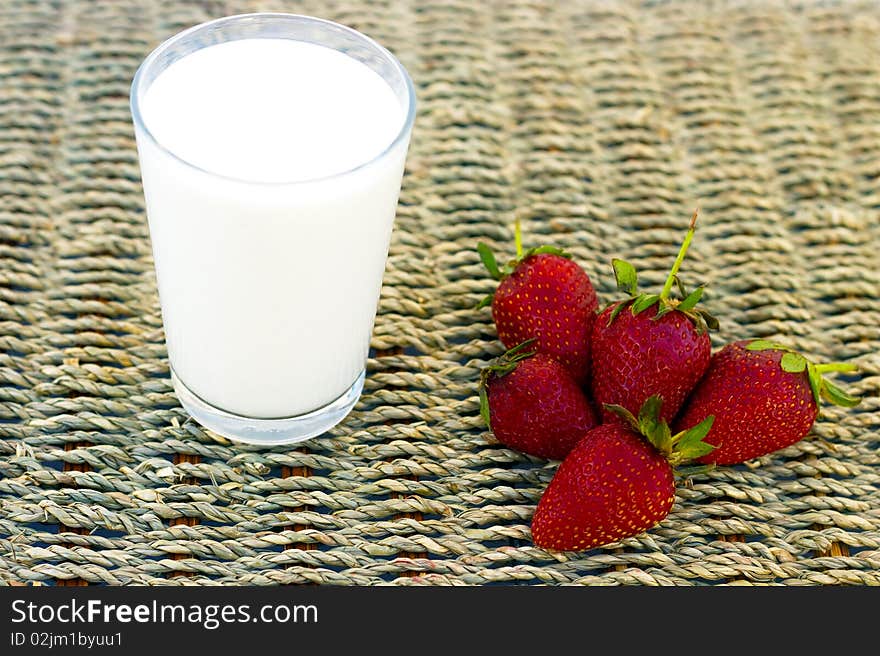 A glass of milk and strawberries in a wicker background