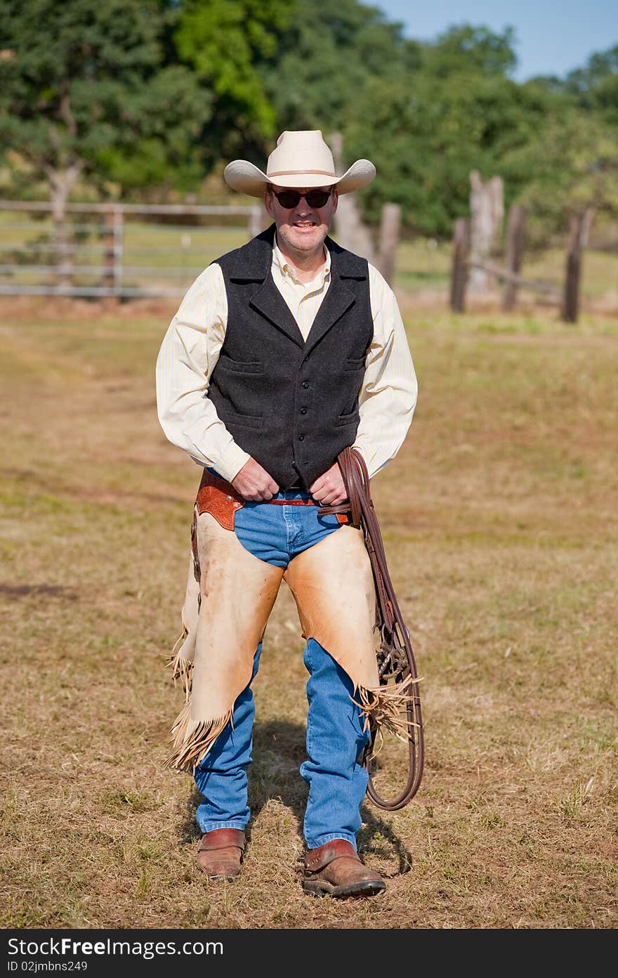 Cowboy walking to his horse with bridle and chaps