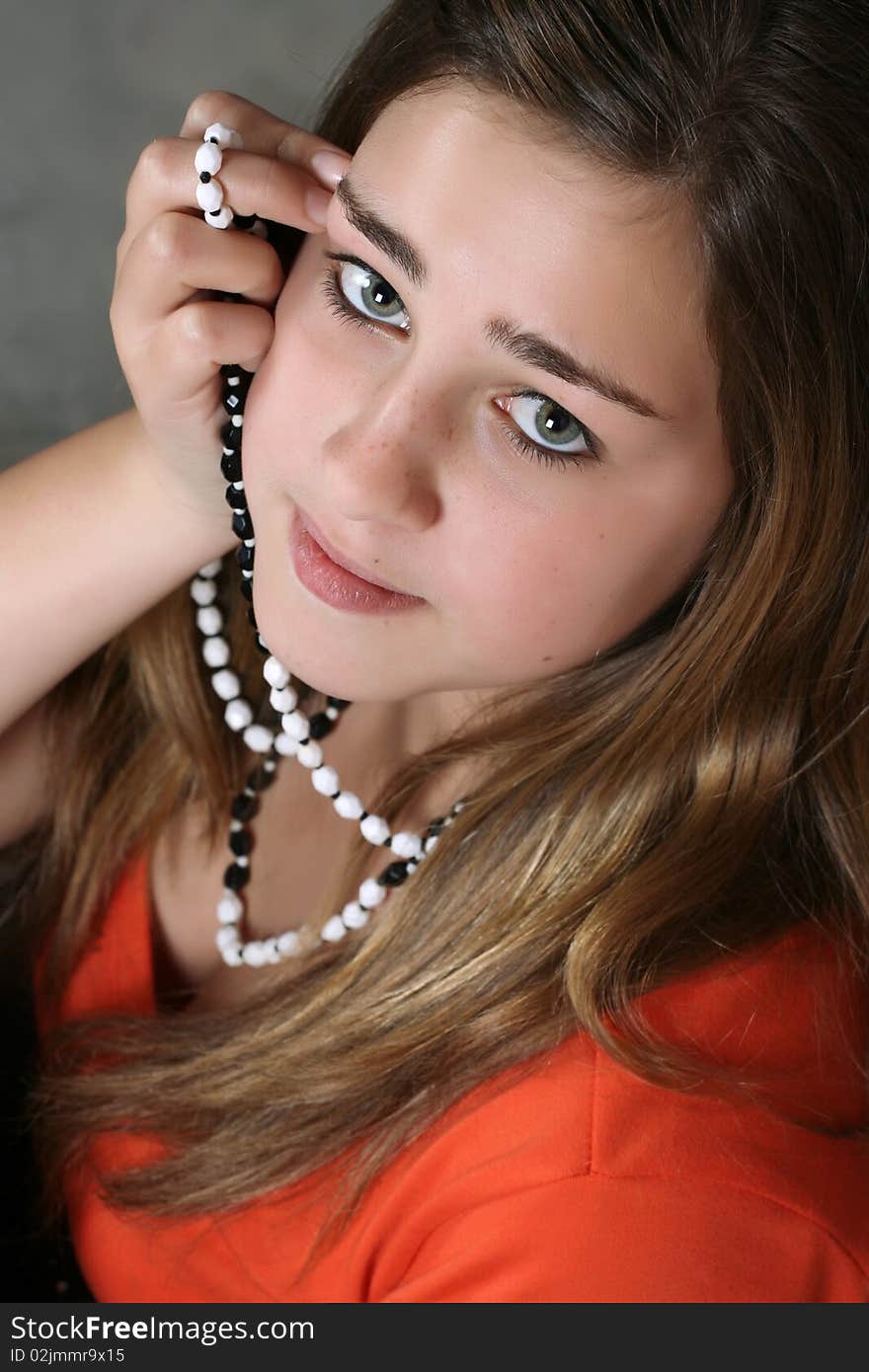 Beautiful teenage female wearing an orange top with necklaces