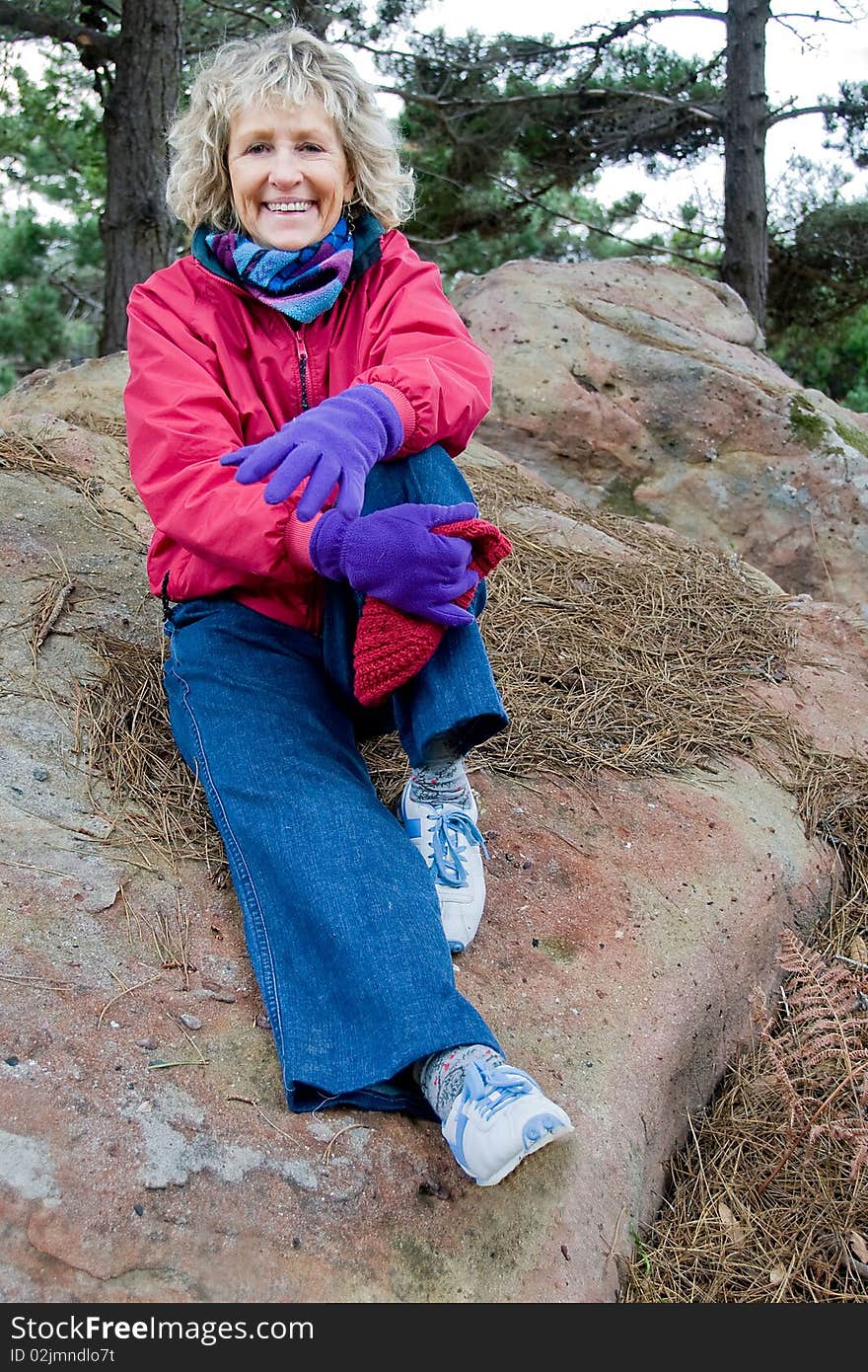 This shot of a senior woman sitting on a rock was taken in natural light on an overcast day. This shot of a senior woman sitting on a rock was taken in natural light on an overcast day.