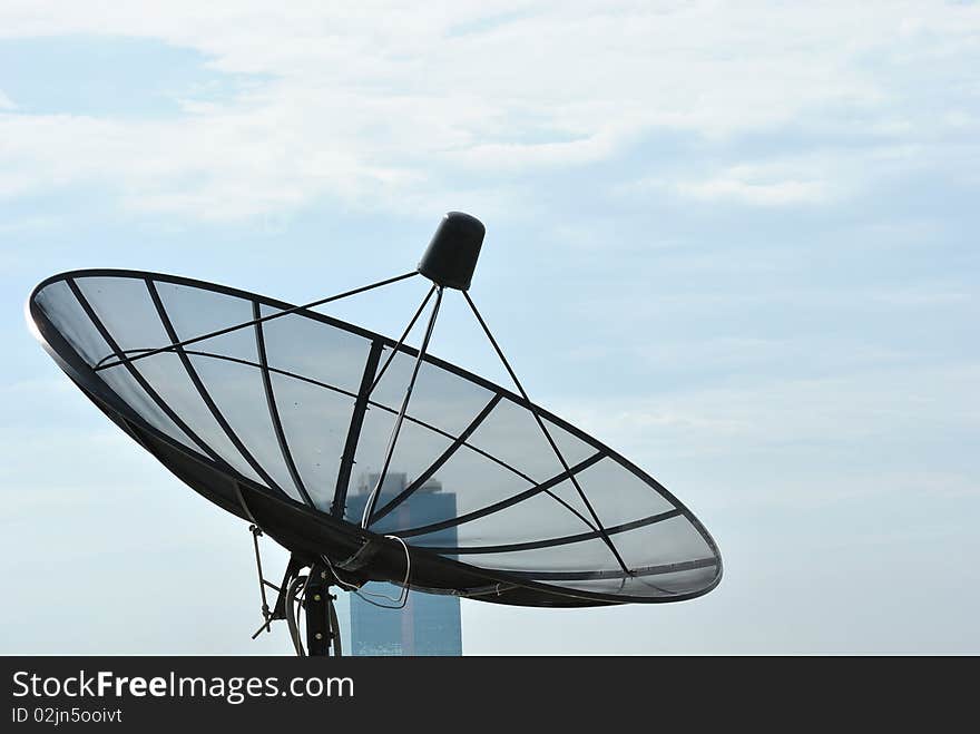 Satellite dish on rooftop and blue sky.