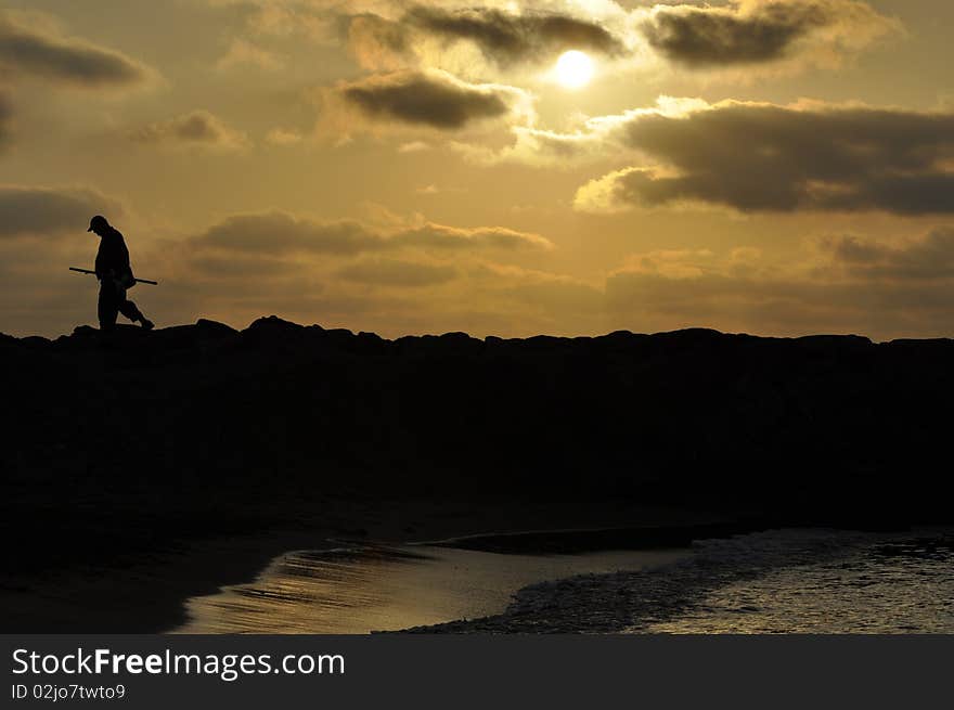 A silhouette of fisherman walking at sunset time. A silhouette of fisherman walking at sunset time