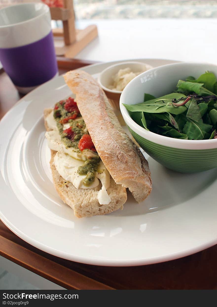 Green salad  and baguette filled with cheese as light lunch for a vegetarian. Green salad  and baguette filled with cheese as light lunch for a vegetarian