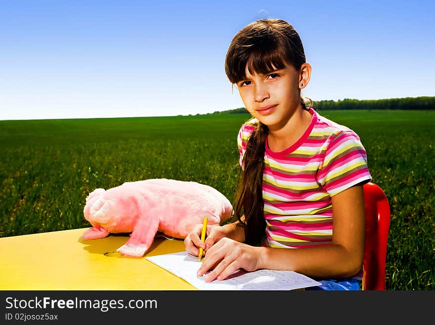 Girl with pen at table in field. Girl with pen at table in field