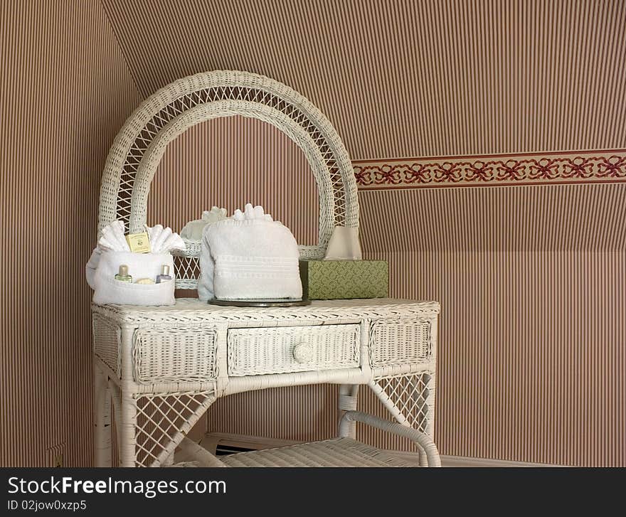 Wicker vanity table with striped wallpaper in an inn