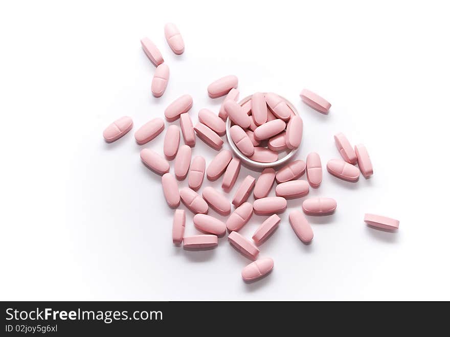 Pink pills lying on a white surface and the lid of the bubble of drugs. Pink pills lying on a white surface and the lid of the bubble of drugs