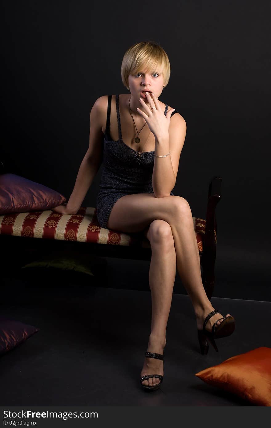 Young beautiful girl sitting on couch isolated on black background. Young beautiful girl sitting on couch isolated on black background