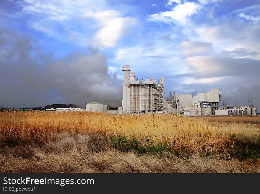 Power plant with wheat grass in the foreground and blue sky's with clouds