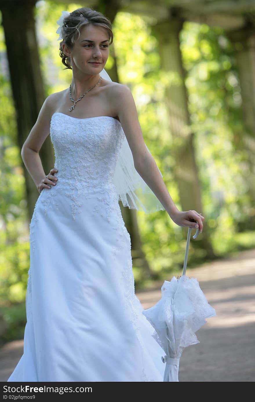 The bride with an umbrella at an ancient column in park. The bride with an umbrella at an ancient column in park