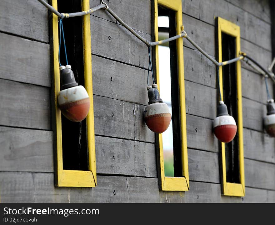 Windows with yellow frame and red bulb attached on a wooden wall, shown as repeated shape and pattern. Windows with yellow frame and red bulb attached on a wooden wall, shown as repeated shape and pattern.