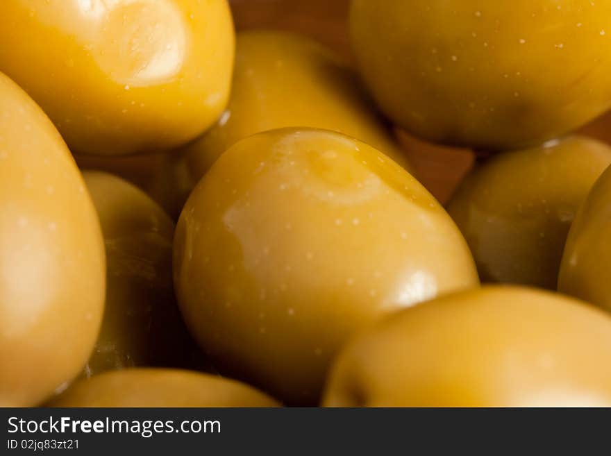 Photo of green olives in a bowl standing on a wood table