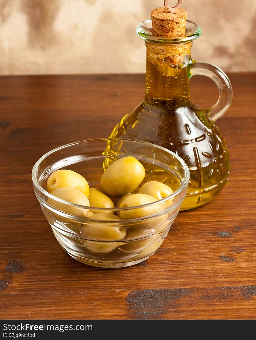 Photo of green olives in a bowl standing on a wood table