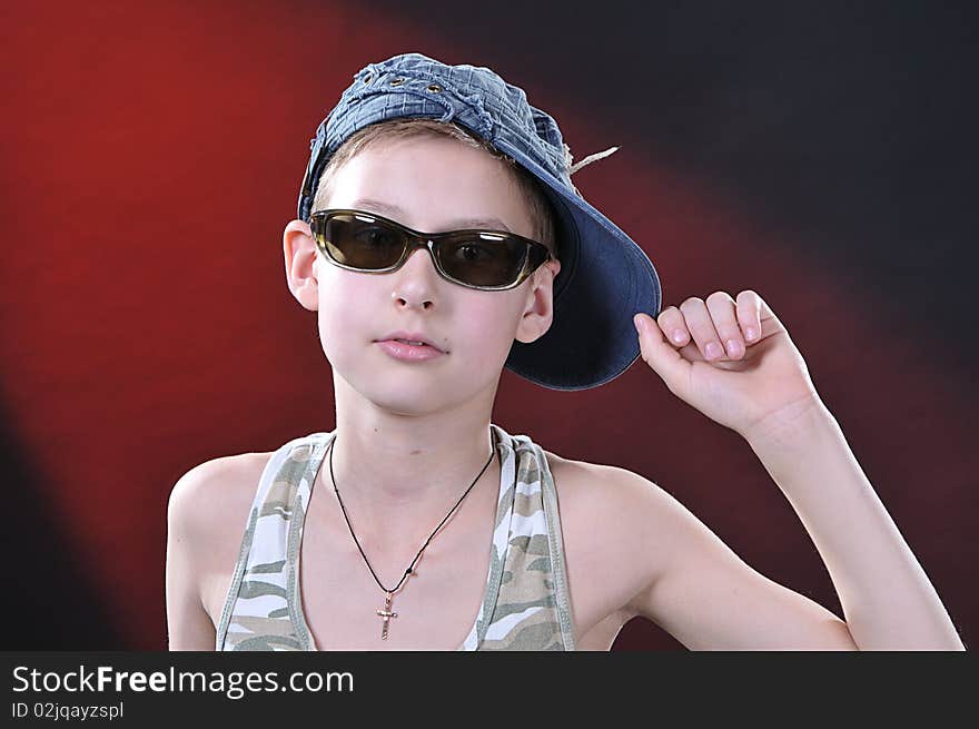 Portrait of is 10-11 years old boy in a jean cap and sun glasses. Portrait of is 10-11 years old boy in a jean cap and sun glasses