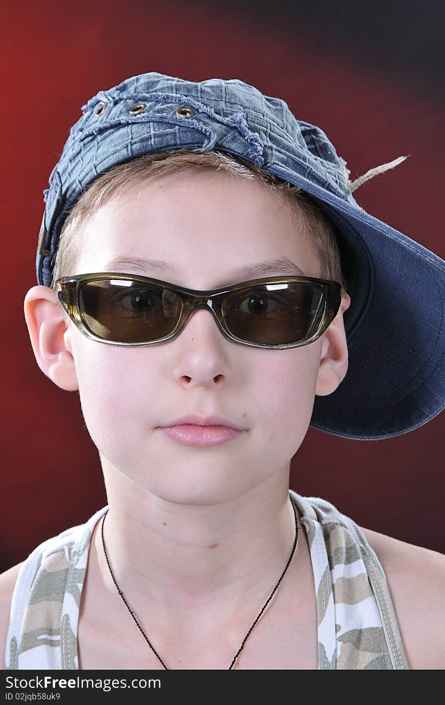 Portrait of is 10-11 years old boy in a jean cap and sun glasses. Portrait of is 10-11 years old boy in a jean cap and sun glasses