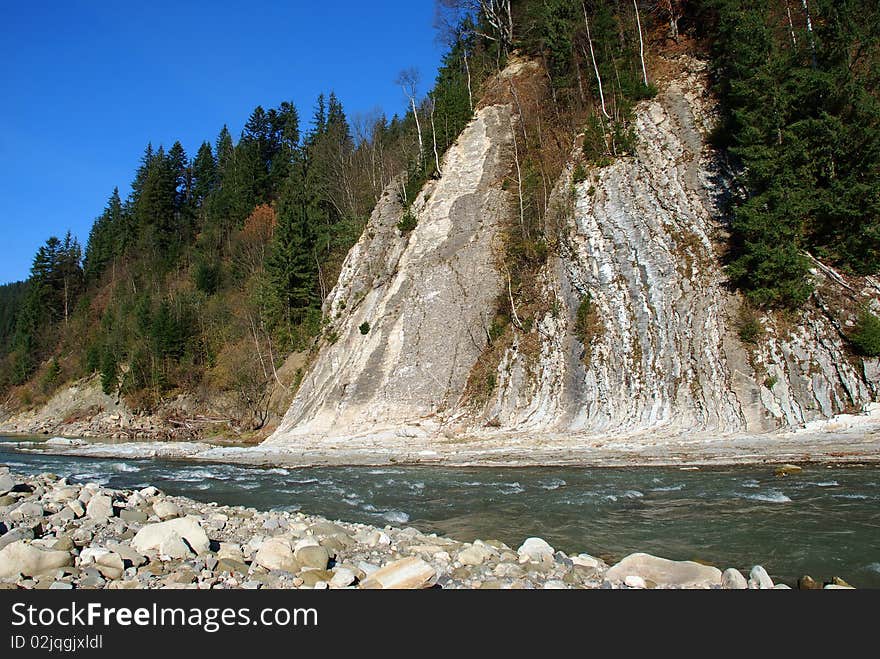 The mountain river under a rock