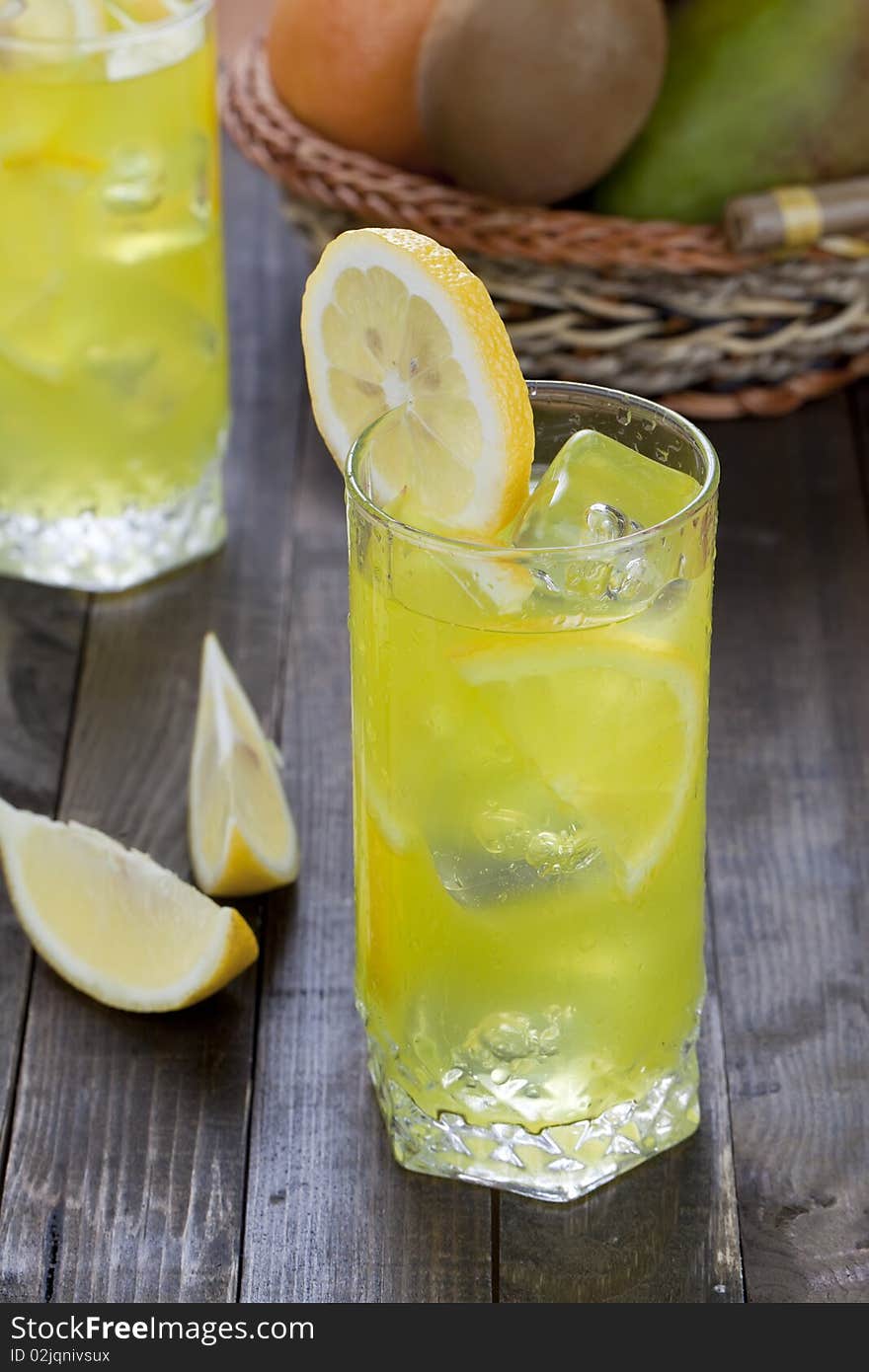 Cold lemon beverage in a wet glass with pieces of the fruit. Cold lemon beverage in a wet glass with pieces of the fruit