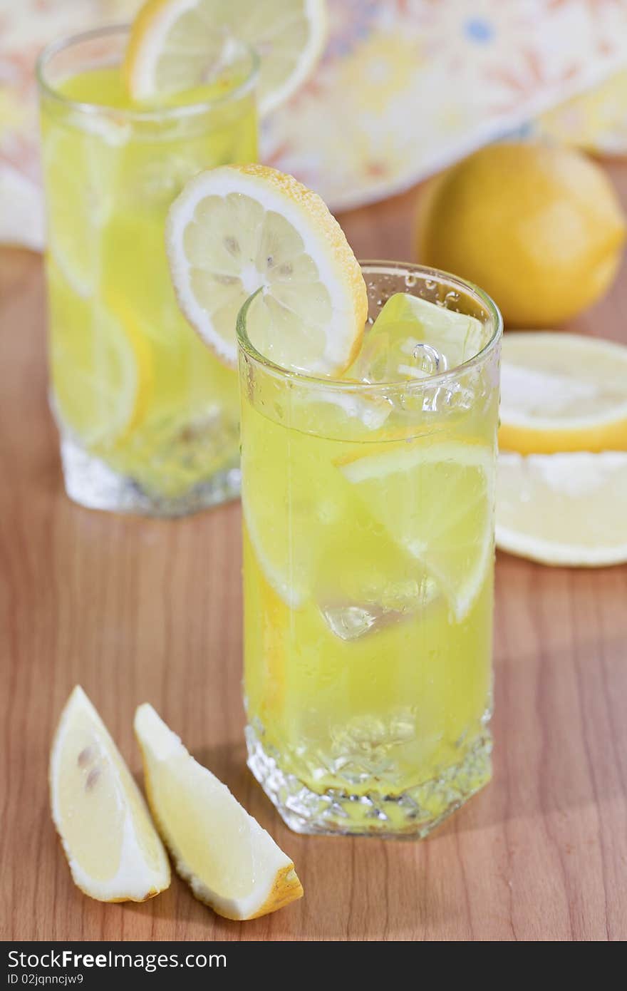 Cold beverage of lemon fruit with ice cubes on wooden table top