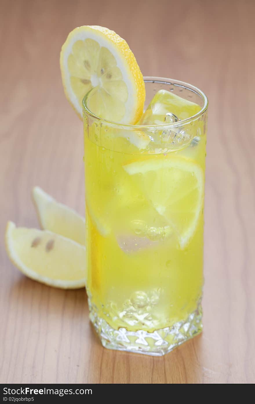 Glass of cold lemon beverage on wooden table top