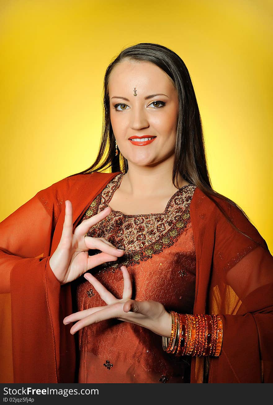 Young beautiful woman in indian traditional jewellary, bindi and sari dress . yellow background. Young beautiful woman in indian traditional jewellary, bindi and sari dress . yellow background