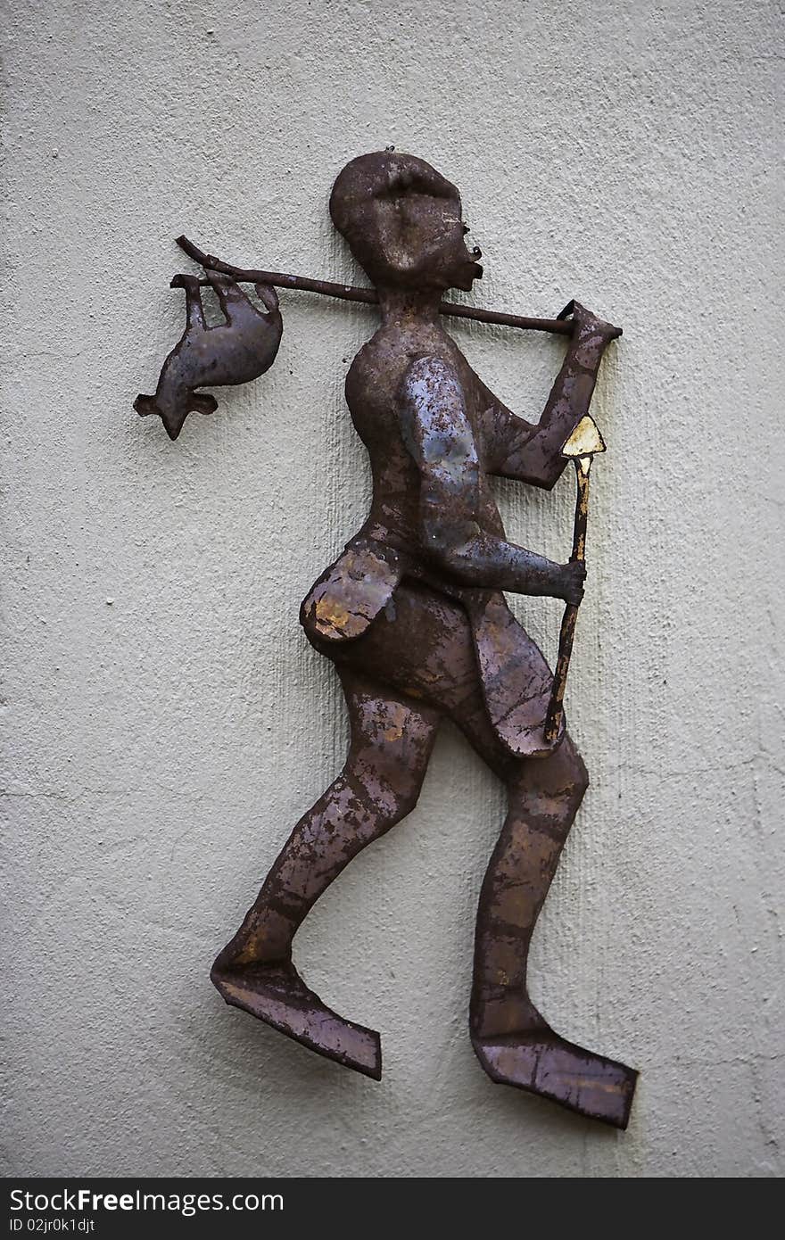 A rusted metal figurine of a native hunter walking with a catch