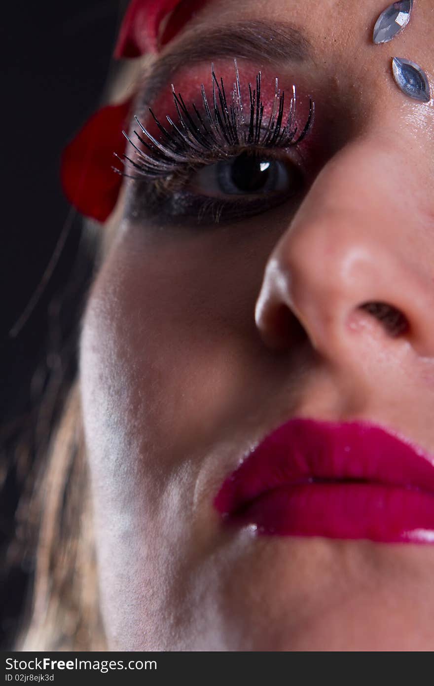 Young fresh woman with an extreme and glamorous makeup and roses on her face. Young fresh woman with an extreme and glamorous makeup and roses on her face.