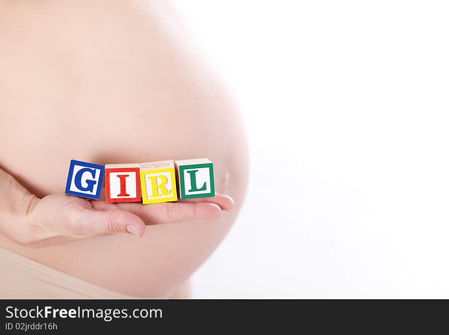 Pregnant belly with wooden playing blocks spelling the word Girl