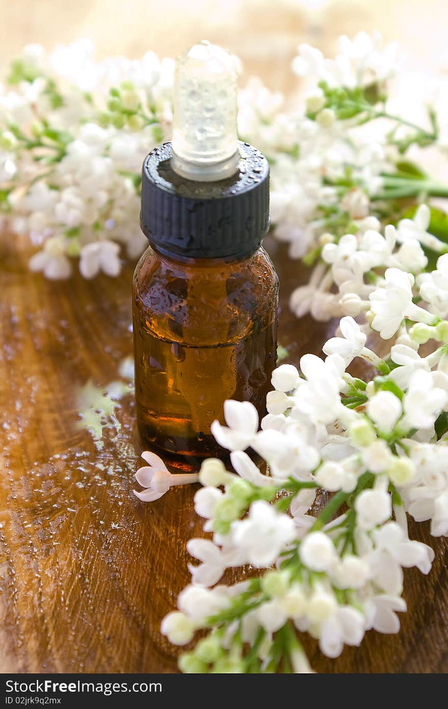 Essential oil bottle with lilac in background