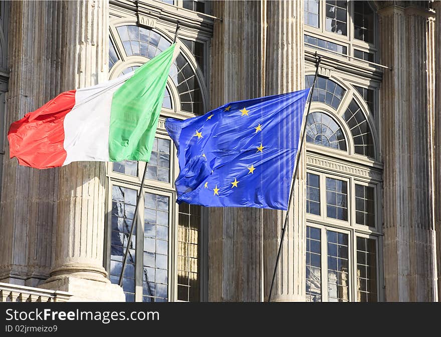 Italian and Eurpean flag in wind on monument facade