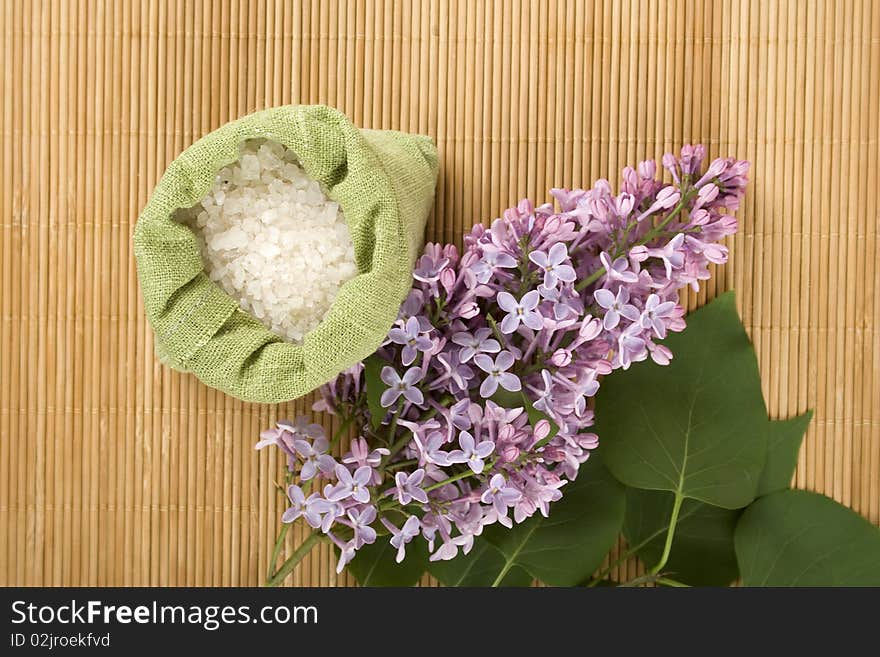 Branch of lilac and green bag with scattered sea salt. Branch of lilac and green bag with scattered sea salt