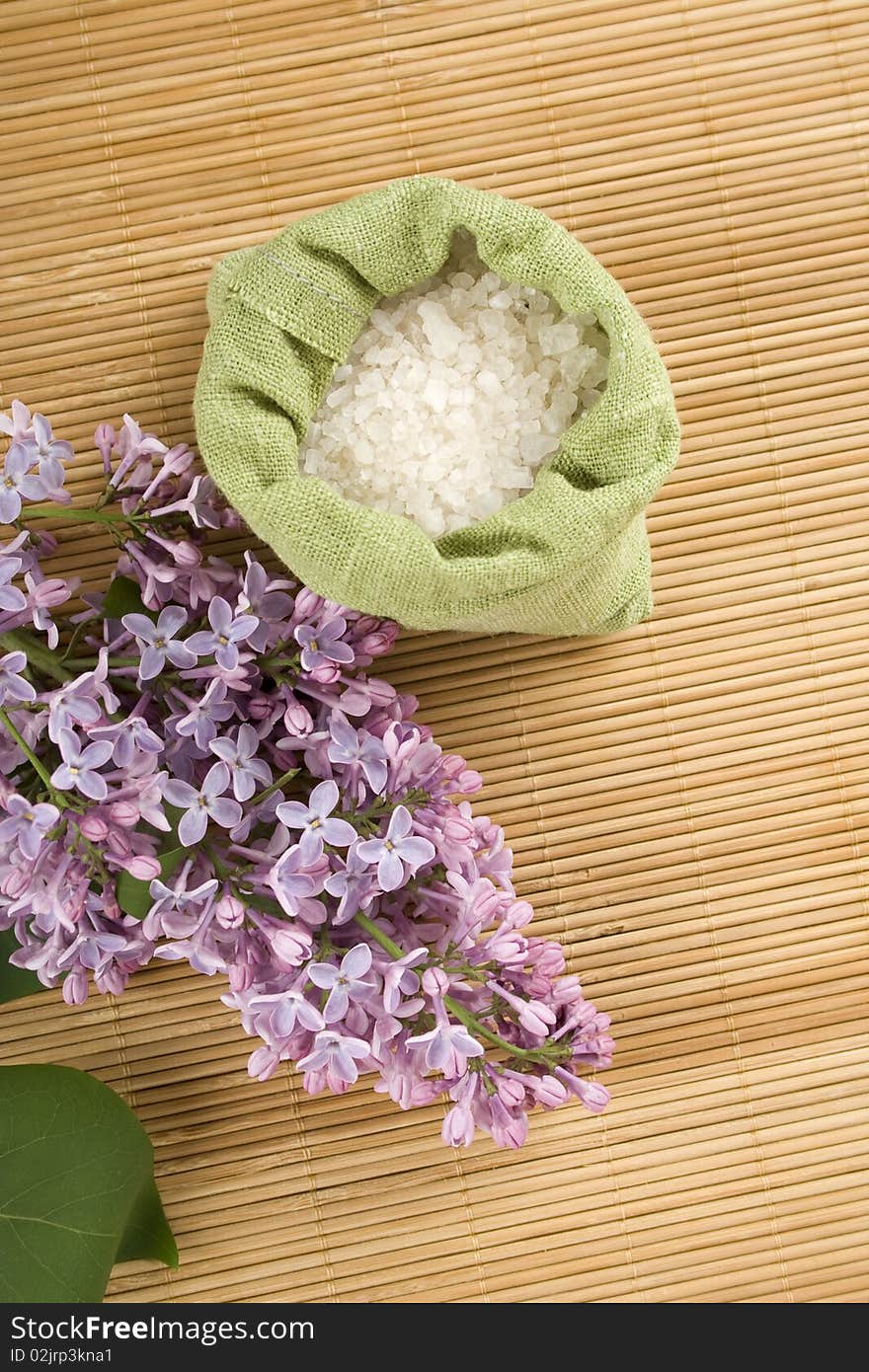 Branch of lilac and green bag with scattered sea salt. Branch of lilac and green bag with scattered sea salt