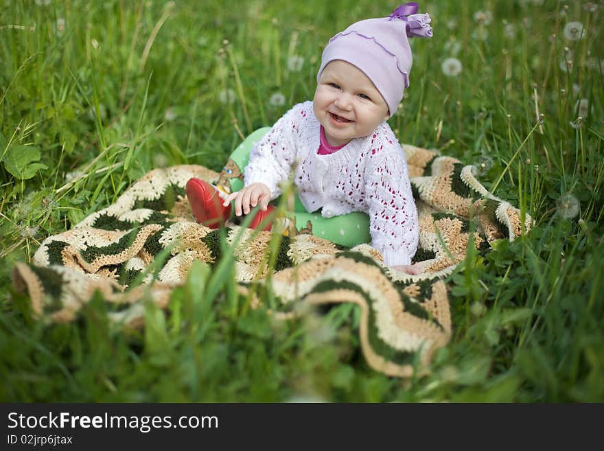 Happy baby on the grass, in the jumper and booties