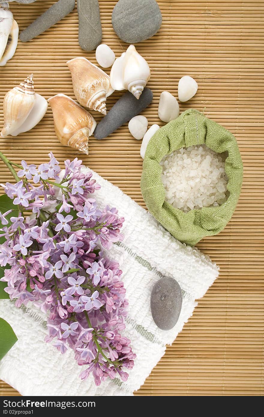 Towel, a branch of lilac and green bag with scattered sea salt. Towel, a branch of lilac and green bag with scattered sea salt