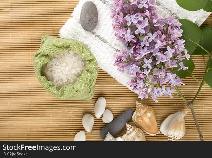 Towel, a branch of lilac and green bag with scattered sea salt. Towel, a branch of lilac and green bag with scattered sea salt