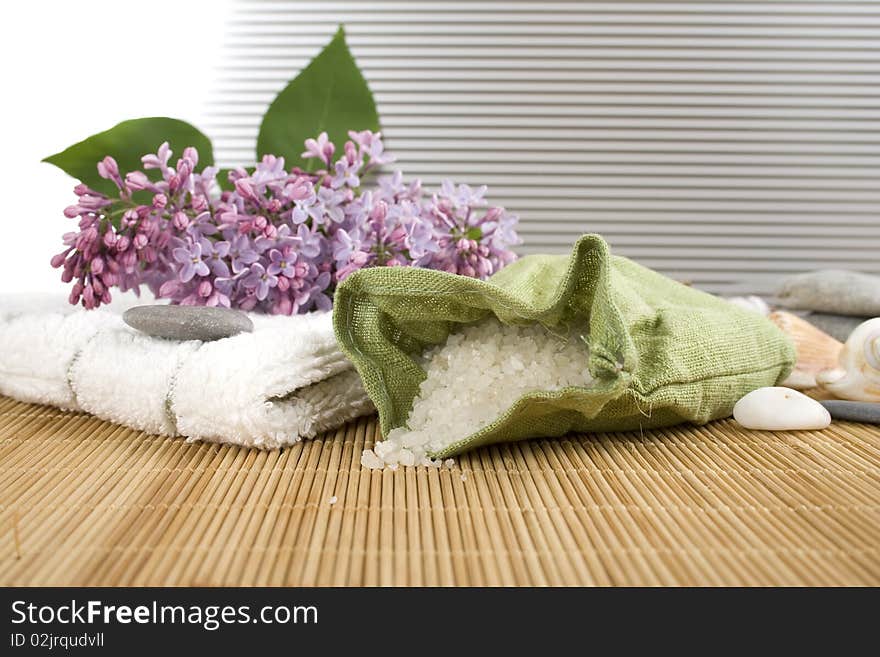 Towel, a branch of lilac and green bag with scattered sea salt. Towel, a branch of lilac and green bag with scattered sea salt