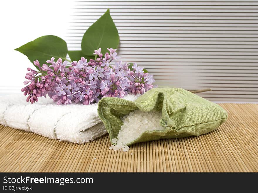 Towel, a branch of lilac and green bag with scattered sea salt. Towel, a branch of lilac and green bag with scattered sea salt