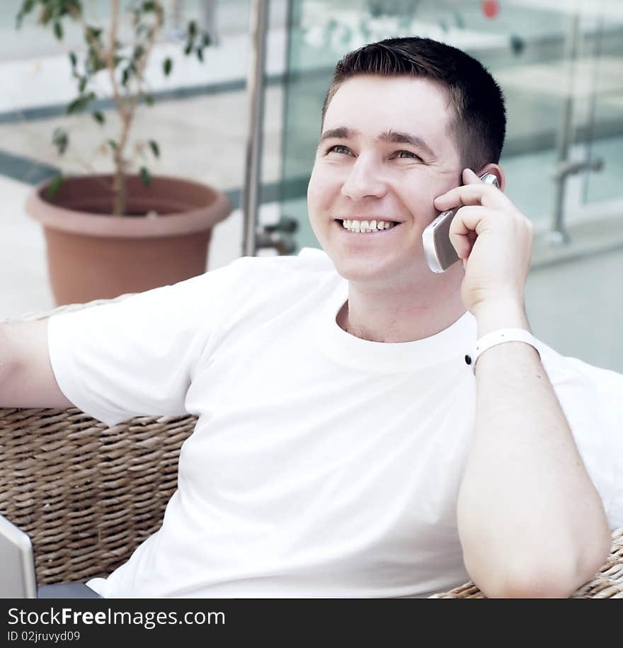 Smiling young man working on laptop computer and call by phone at home