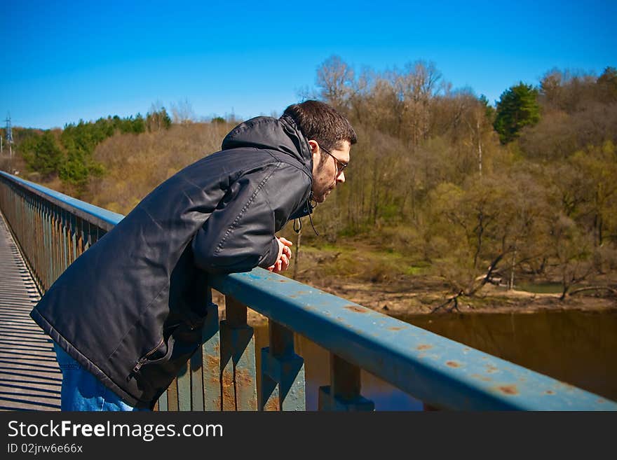 Man standing on a bridge and looking down on the river