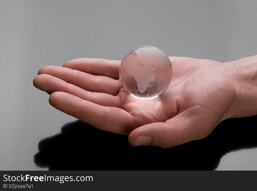 Glass globe in hand on black glossy background