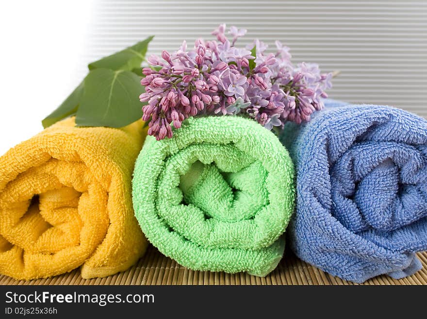 Colored towels folded lie next to them a branch of lilac. Colored towels folded lie next to them a branch of lilac