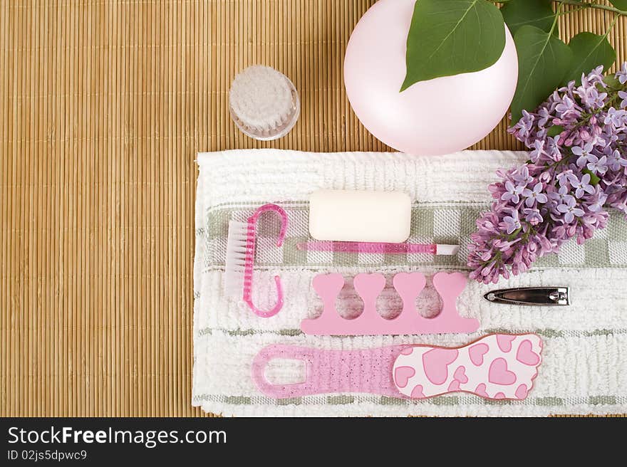 On the wooden table flowers, cream, soap, a brush for cleaning the face and pink pedicure set. On the wooden table flowers, cream, soap, a brush for cleaning the face and pink pedicure set