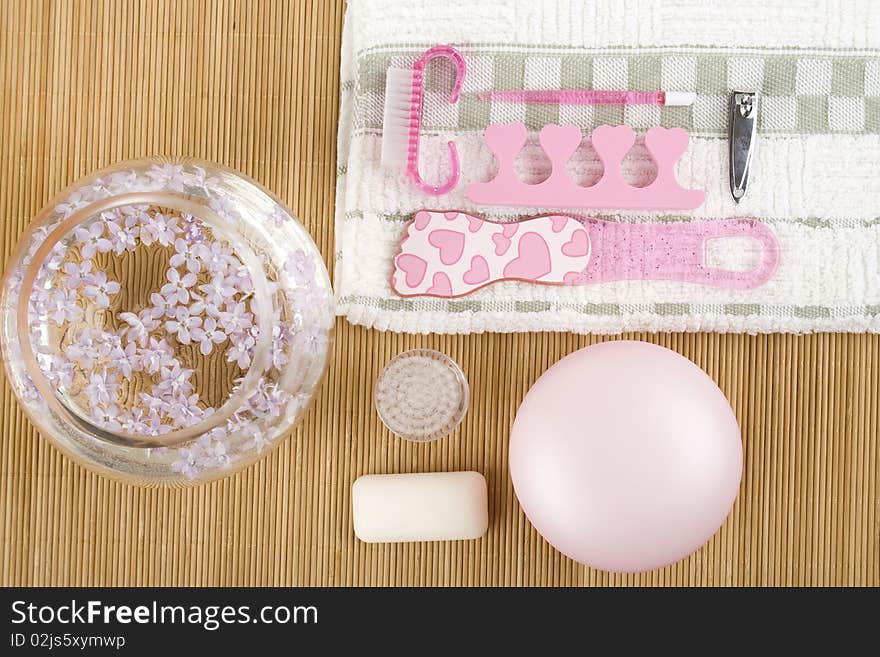 On the wooden table flowers, cream, soap, a brush for cleaning the face and pink pedicure set. On the wooden table flowers, cream, soap, a brush for cleaning the face and pink pedicure set