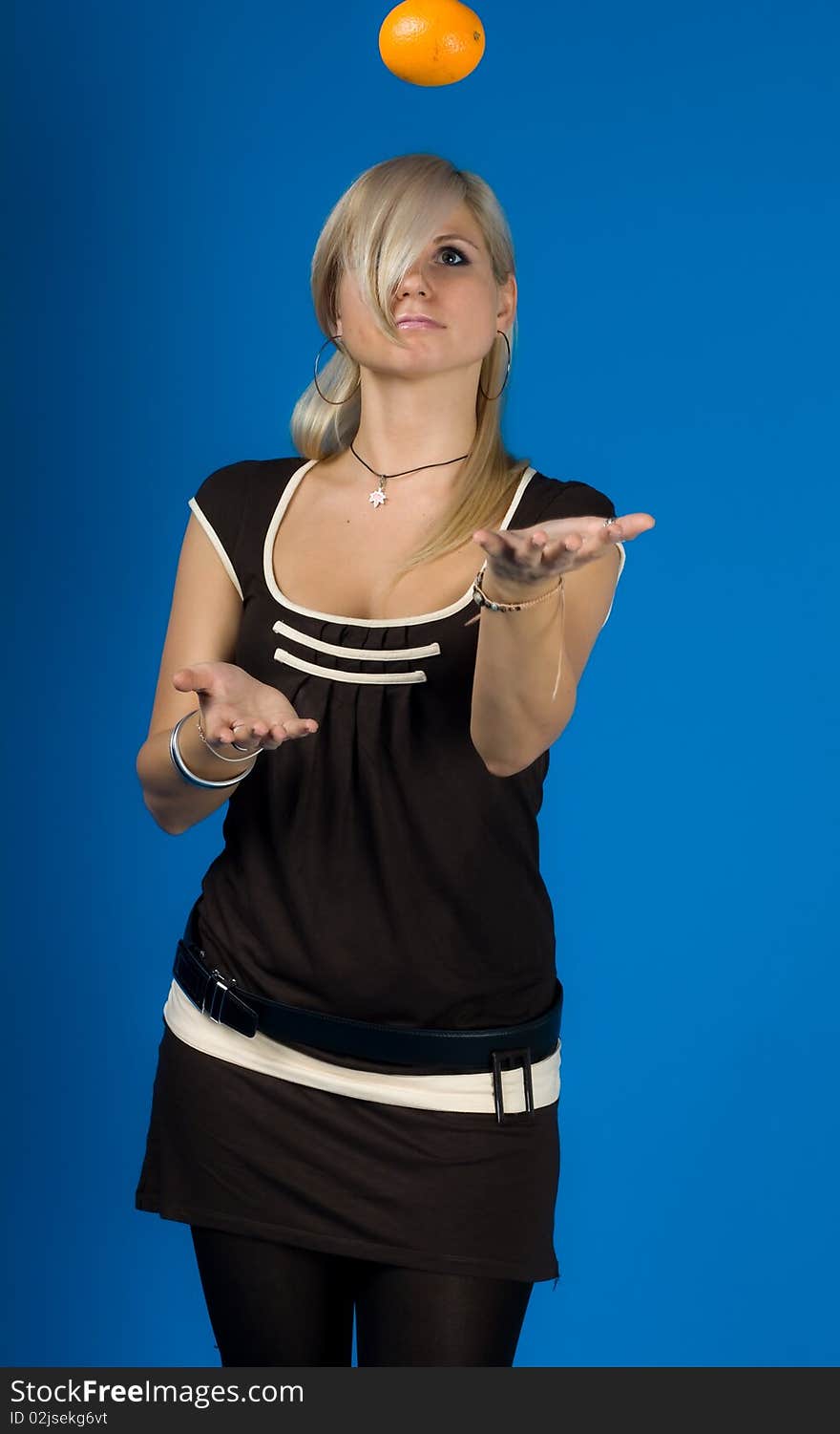 Beautiful young woman holding an orange isolated on blue background. Beautiful young woman holding an orange isolated on blue background