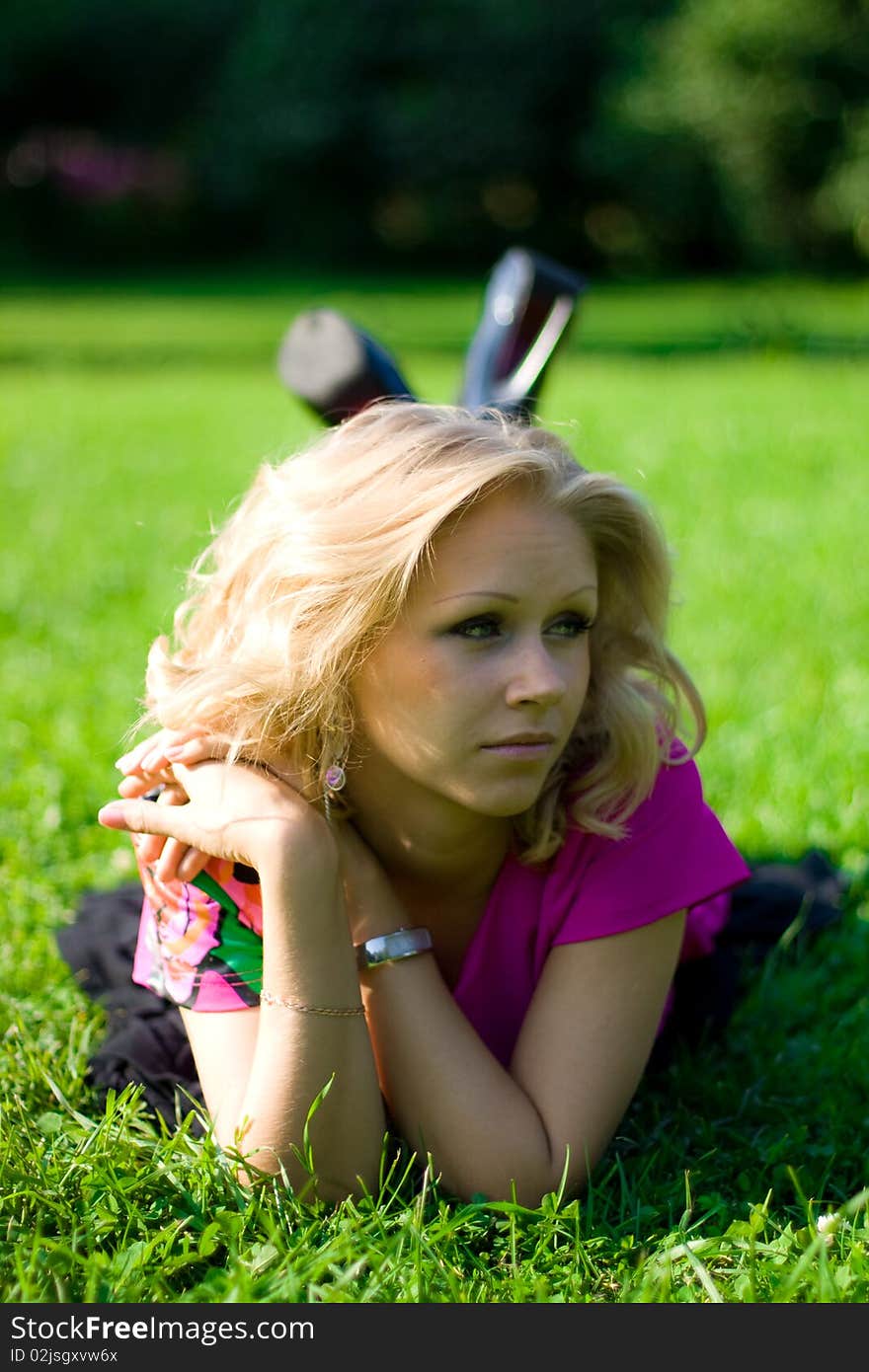 Young beautyful girl lying on grass on a sunny day in a park. Young beautyful girl lying on grass on a sunny day in a park