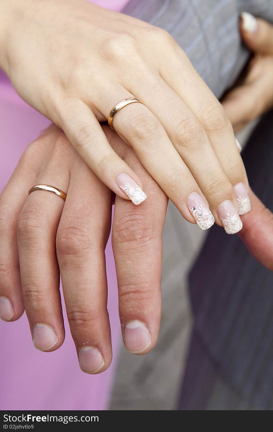 Bride and groom holding hands together show their rings