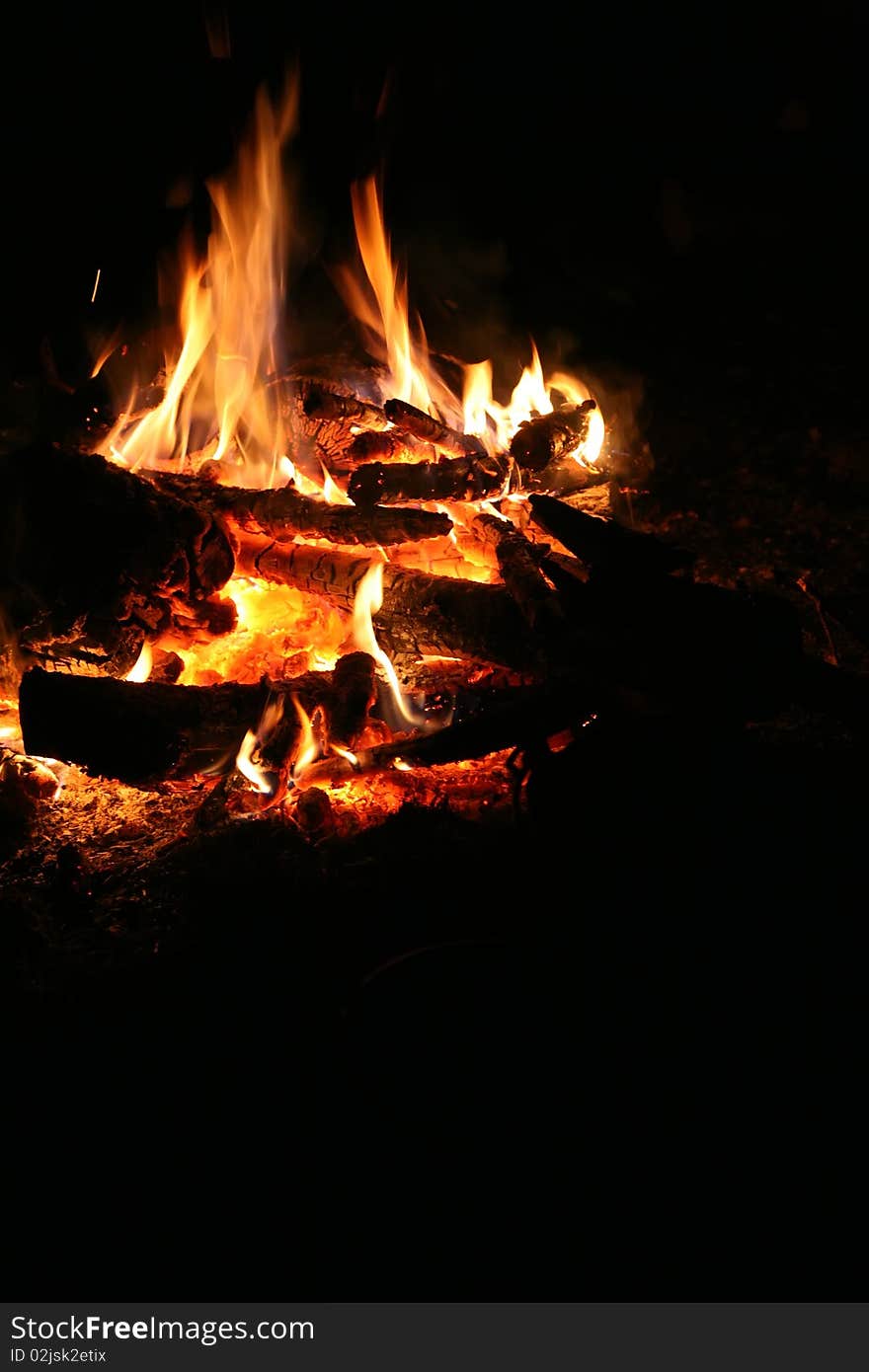 Orange tongues of flame of a tourist fire on a black background of night. Orange tongues of flame of a tourist fire on a black background of night