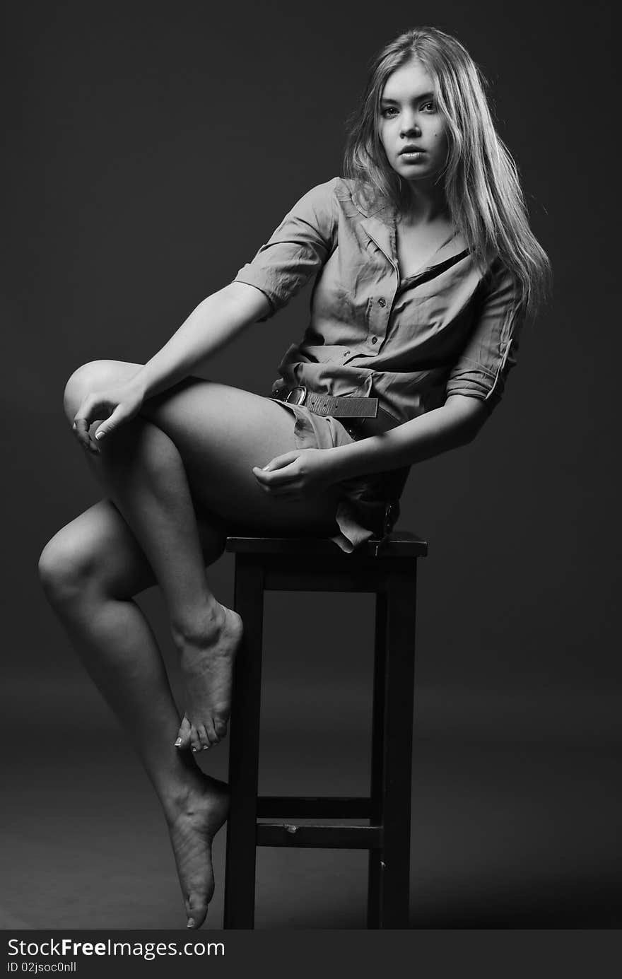 Black and white shot of girl sits on chair with naked legs